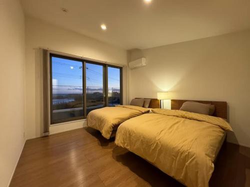 ein Schlafzimmer mit zwei Betten und einem großen Fenster in der Unterkunft Shirahama Village - Vacation STAY 53444v in Minamiboso