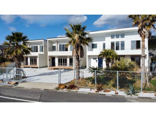 a white building with palm trees in front of it at Shirahama Village - Vacation STAY 52778v in Minamiboso