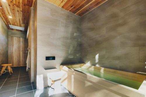 a bathroom with a tub and a wooden ceiling at moon river - Vacation STAY 53517v in Hatsukaichi