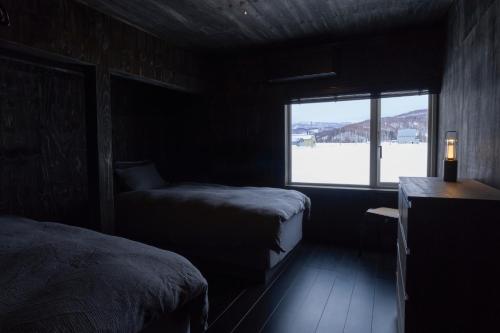 Cette chambre sombre comprend 2 lits et une fenêtre. dans l'établissement DAICHI Niseko HUT - Vacation STAY 18699, à Kutchan