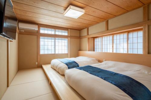 two beds in a room with two windows at Miyabi Sengokuhara Hot Spring Villa - Vacation STAY 60344v in Sengokuhara