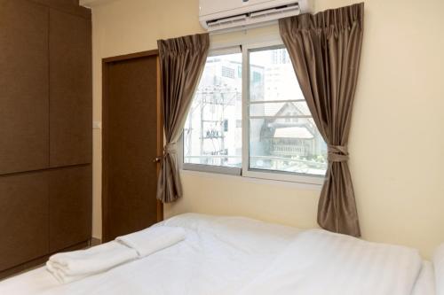 a bedroom with a bed and a window at Sea Inn Pattaya in Pattaya Central