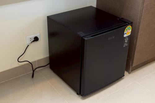a black refrigerator sitting next to an electrical outlet at Sea Inn Pattaya in Pattaya Central