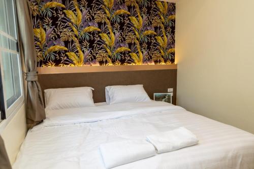 a bed in a bedroom with a painting on the wall at Sea Inn Pattaya in Pattaya Central