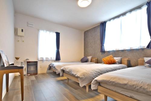 a room with three beds and a desk and two windows at GUESTHOUSE LE REPOS - Vacation STAY 18746 in Abashiri