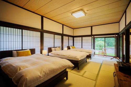 two beds in a room with windows at kominka Higurashi-an - Vacation STAY 18803 in To-katta