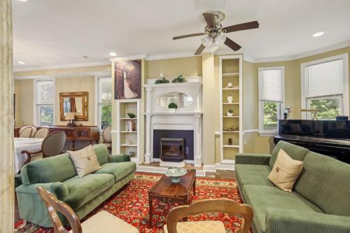 a living room with green couches and a fireplace at Charming Victorian Home with Porch & Large Yard home in Catonsville