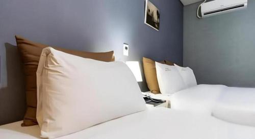 a bedroom with two beds with white sheets and pillows at BENIKEA Technovalley Hotel in Daejeon