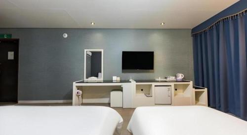 a bedroom with two beds and a desk and a tv at BENIKEA Technovalley Hotel in Daejeon