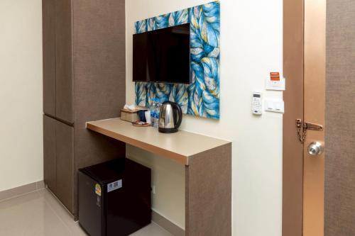 a hotel room with a desk with a tv on the wall at Sea Inn Pattaya in Pattaya Central