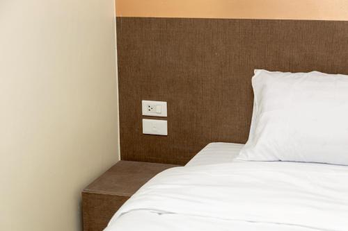 a bed with white sheets and a brown head board at Sea Inn Pattaya in Pattaya Central
