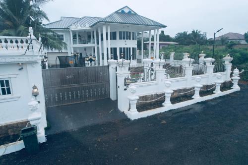 a white fence in front of a white house at The Peacock Mansion in Kumasi