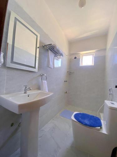 a white bathroom with a sink and a toilet at kisimani Nest in Mombasa