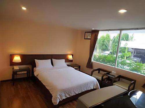 a bedroom with a bed and a large window at Dusit Hotel in Sakon Nakhon