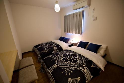 two beds in a small room with blue pillows at Plus Life Ohama - Vacation STAY 85882v in Miyara