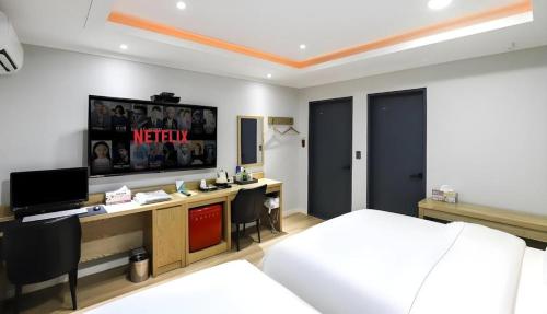 a bedroom with a bed and a desk with a television at Hotel Primo Daejeon in Daejeon