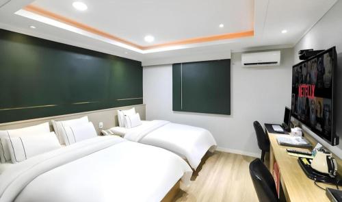 a bedroom with a large white bed and a television at Hotel Primo Daejeon in Daejeon