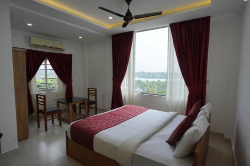 a bedroom with a bed and a desk and windows at Parassini Tourist Home in Parassinikadavu