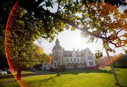 a large white building on a field with trees at Hellidens Slott in Tidaholm