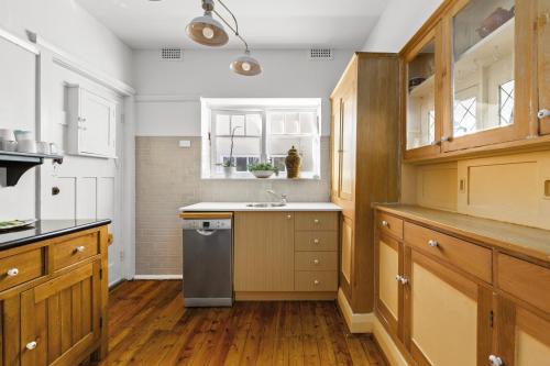a large kitchen with wooden cabinets and a sink at Fairlight 2-Bed Apartment Steps from the Beach in Sydney