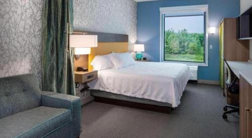 a hotel room with a bed and a couch and a window at Home2 Suites by Hilton Raynham Taunton in Raynham