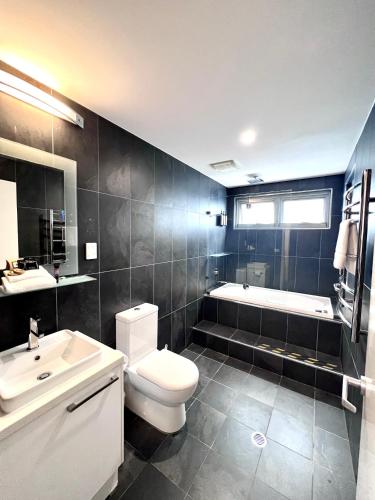 a bathroom with a toilet and a tub and a sink at Crown on Darby Newcastle in Newcastle