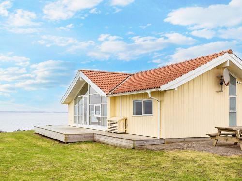 a small white house with a picnic table and a table at 4 person holiday home in Vinderup-By Traum in Vinderup