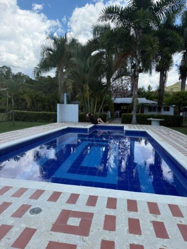 a blue swimming pool with palm trees in the background at Eco Hotel Rancho J en Tulua Valle in Morales