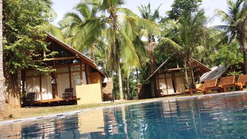 a resort with a swimming pool and palm trees at Kottawatta Village in Udawalawe