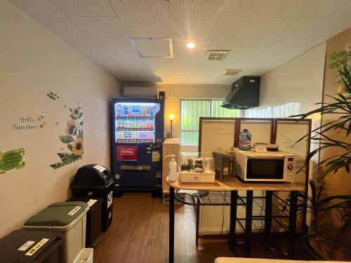 a room with a table with a microwave on it at 民宿さざんか in Okinawa City
