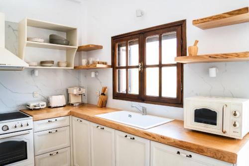a kitchen with white cabinets and a sink and a window at Xenoula Suite in Sitia