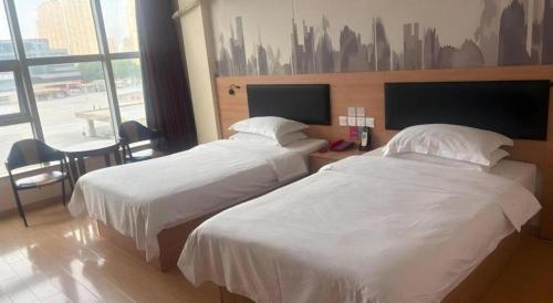 a hotel room with two beds and a large window at Thank Hotel Jiangxi Jiujiang Lianxi District Railway Station Square in Jiujiang
