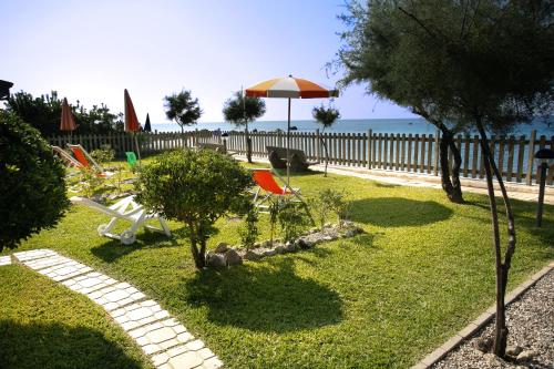 a yard with lawn chairs and an umbrella at Le Casette Sul Mare in Capo Vaticano