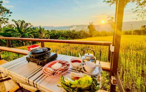 a picnic table with food and wine and a field at Heaven Hill Camping in Ban Thung Na