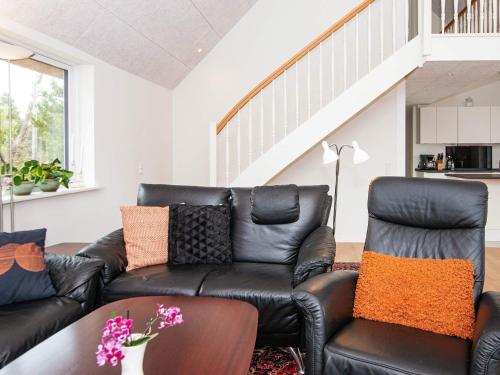 a living room with a black leather couch at 6 person holiday home in Rømø-By Traum in Toftum