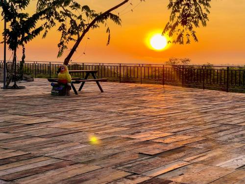a girl sitting on a bench watching the sunset at Thisak Resort Cheung phnom kulen in Siem Reap