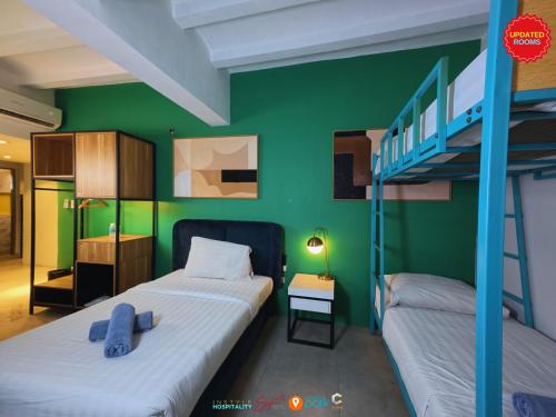 two beds in a room with a green wall at Citizen Hotel in Manila
