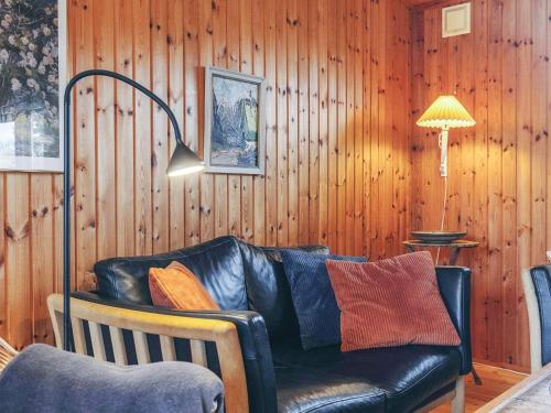 a black leather couch in a room with wooden walls at 4 person holiday home in Store Fuglede in Store Fuglede