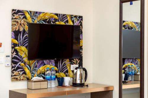 a tv on a wall with a tropical wallpaper at Sea Inn Pattaya in Pattaya Central
