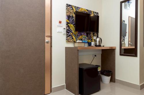 a room with a desk and a tv and a door at Sea Inn Pattaya in Pattaya Central