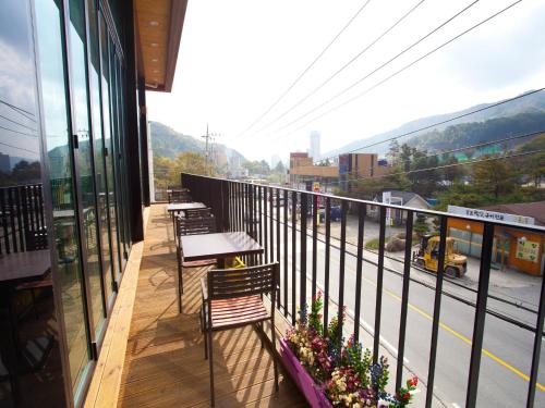 a balcony with tables and chairs and a view of a street at White Cabin in Pyeongchang 