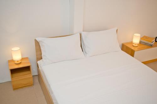 a bedroom with a white bed with two lights on tables at Singah in Bukit Mertajam