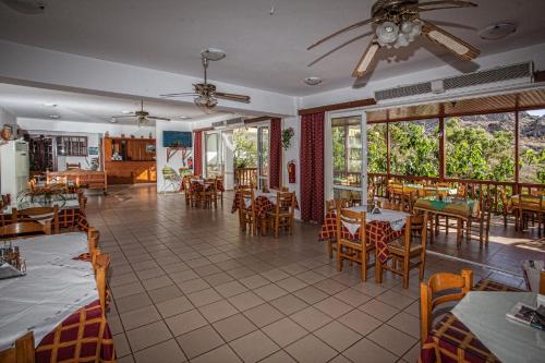 un restaurante con mesas, sillas y ventanas en Ammoudi Hotel, en Damnoni