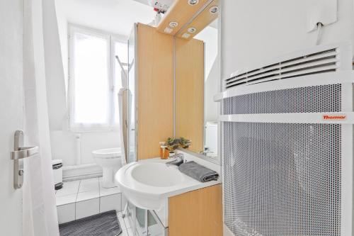 ein weißes Badezimmer mit Waschbecken und Toilette in der Unterkunft Center of Paris Luxurious Studio Apartment Free NetFlix in Paris