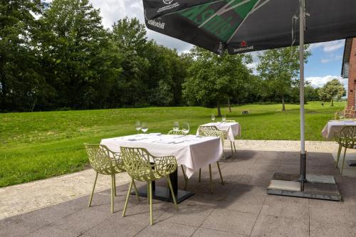 two tables and chairs under an umbrella on a patio at ESSTRA Hotel Erica in Erica