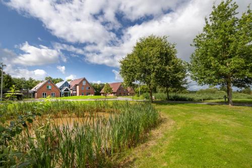 a house in a field with a pond and trees at ESSTRA Hotel Erica in Erica