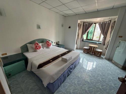 a bedroom with a large bed with pink pillows at Karon Cove at Seabreeze Inn in Karon Beach