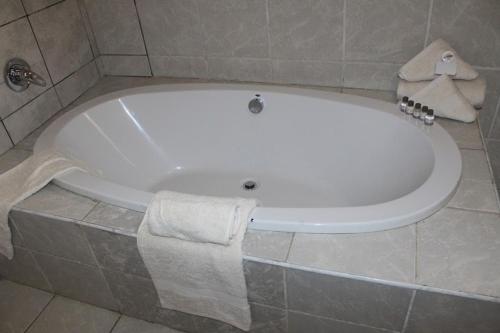 a white bath tub in a bathroom with towels at Flamboyant Guest Lodge in Johannesburg