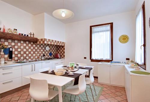 una cucina con armadi bianchi, tavolo e sedie di B&B 500 a Lido di Venezia