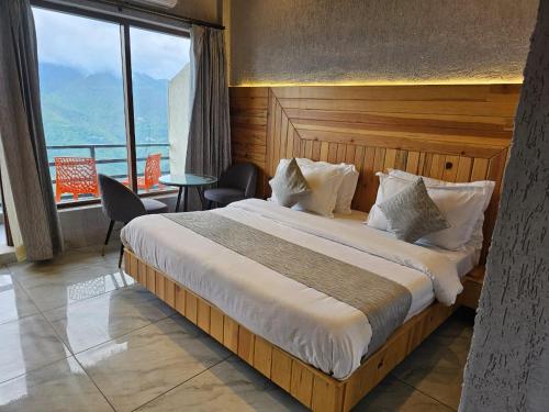 a bedroom with a large bed with a large window at Jhingola Bola Mount in Mussoorie